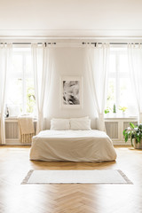 Wall Mural - Poster above white bed in spacious bright bedroom interior with windows and rug. Real photo