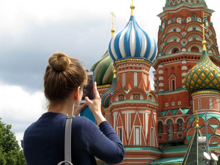 Woman tourist taking pictures with smartphone the St. Basil's cathedral on Red square in Moscow. Tourism in Russia