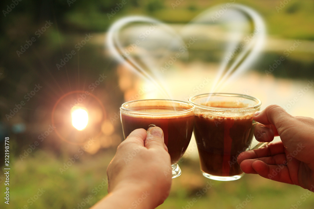 Dwie szklane filiżanki kawy w dłoniach kobiety przy zachodzie słońca. - obrazy, fototapety, plakaty 