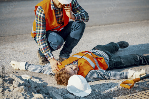Fotografía Worried man calling ambulance for his unconscious coworker