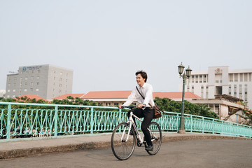 lifestyle, transport and people concept - young man with headphones riding bicycle on city street