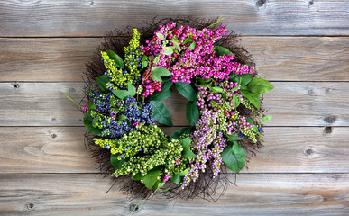 Wall Mural - Colorful artificial wreath made of flowers and leaves on vintage wooden background