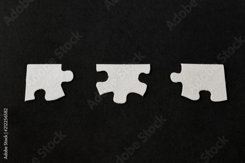 Fotografie, Obraz White jigsaw puzzle pieces on black background;
