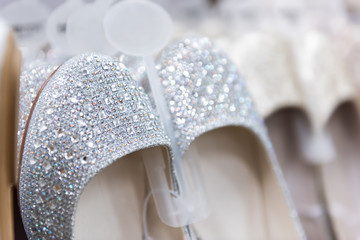 Closeup of many shining ballet flat style flats shoes embellished with crystals, pearls, embellishments on retail display in wedding store, shop, shopping mall