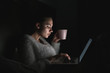© mnelen.com - business young girl freelancer sitting in bed late at night, working on her laptop and drinking tea