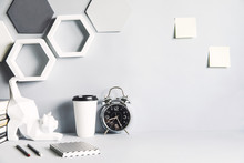 Modern And Design Space With Cat Figures, Clock, Memo Sticks, Office Accessories And Cup Of Coffee. Gray Interior With Hanging Hexagone Shapes. Design Gray Room.