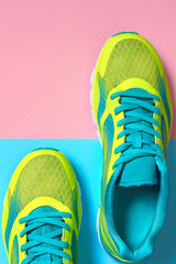 Pair of sport shoes on colorful background. New sneakers on pink and blue pastel background, copy space. Overhead shot of running shoes. Top view, flat lay