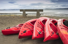 Empty Red Plastic Recreational Kayaks For Rent Or Hire, Stored On Sandy Beach After Hours On A Rainy Day. Crescent Beach, Surrey, British Columbia, Canada.