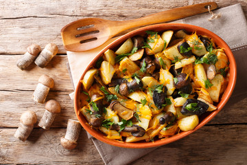 Organic food: baked wild mushrooms with potatoes, dill, parsley and cheddar cheese in a baking dish close-up. horizontal top view