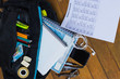 © Arturo - Regreso a clases con la mochila llena de libretas y accesorios como plumas, tijeras, audífonos, horario de clases, sobre un fondo de madera
