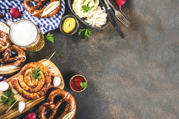 Oktoberfest food menu, bavarian sausages with pretzels, mashed potato, sauerkraut, beer bottle and mug, dark rusty background copy space top view