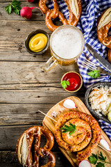 Oktoberfest food menu, bavarian sausages with pretzels, mashed potato, sauerkraut, beer bottle and mug old rustic wooden background, copy space above