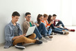 © Africa Studio - Group of teenagers with modern devices sitting on floor near wall