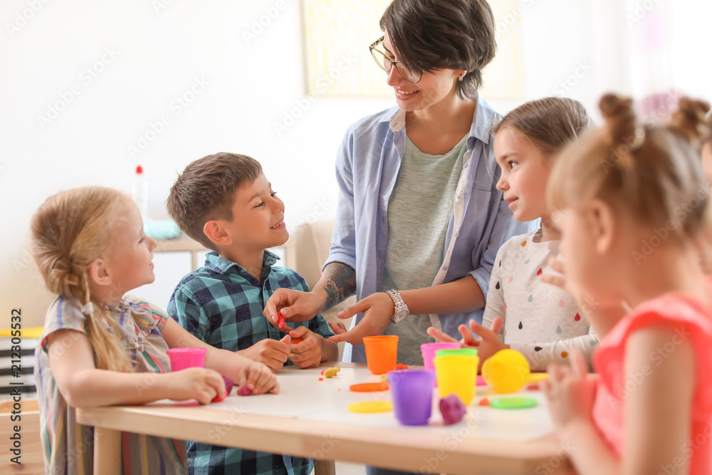 Young woman playing with little children indoors - obrazy, fototapety, plakaty 