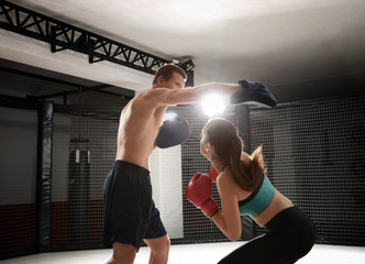 Wall Mural - Young female boxer training in gym with personal coach