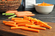 Wooden board with carrot sticks on table