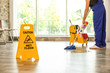 © New Africa - Safety sign with phrase Caution wet floor and cleaner indoors. Cleaning service