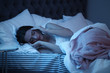 © New Africa - Young woman suffering from headache while lying in bed at night. Sleeping problems