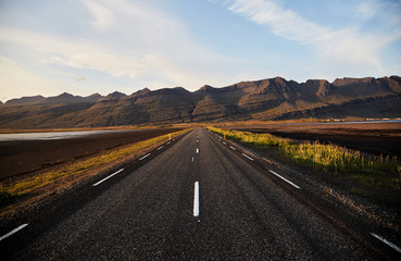 Wall Mural - The road to the horizon in Iceland. Typical Iceland landscape with road and mountains. Summer time.