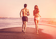 Young couple running on the beach at sunset