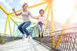 Happy women friends jumping on colorful bridge on sunny day