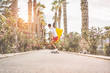 Young man riding longboard around city streets holding boogie surf board