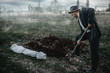 Killer is digging a grave for the victim in forest