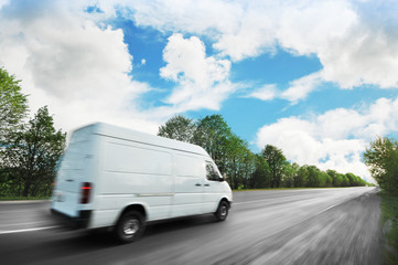 Big van in motion on the countryside road shipping goods against sky