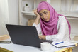 A Muslim woman wearing a hijab is tired of working in the office by the computer. Arab girl in the workplace.