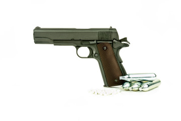 Profile view of isolated semi-automatic airsoft handgun with bullets and gas container. Replica of real handgun on white background.