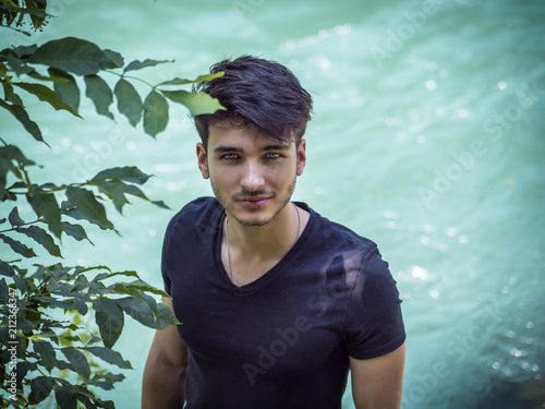 Young Man With Green Eyes Standing By A River Looking Up At
