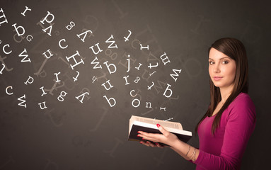 Wall Mural - Casual young woman holding book with white alphabet flying out of it