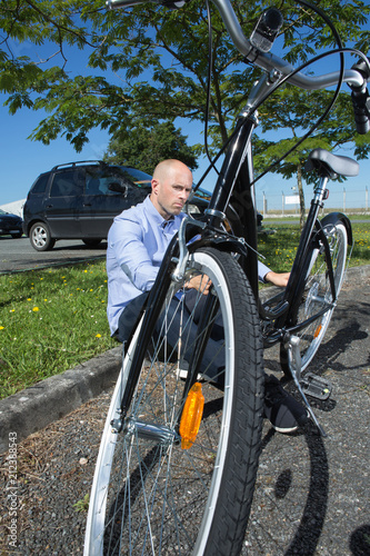 Fotografie, Obraz annoyed man sitting at the park next to bicycle