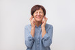 © Viktor Koldunov - Studio portrait of attractive mature woman in blue shirt having excited, superstitious and naive look, keeping fingers crossed, hoping to win lottery or her team win