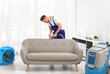 © New Africa - Dry cleaning worker removing dirt from sofa indoors