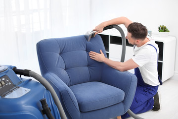 Canvas Print - Dry cleaning worker removing dirt from armchair indoors