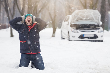 Frustrated driver next to broken car. Winter season road trip problems and assistance concept.