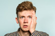 scared shocked terrified frightened startled man clutching hands to his face. portrait of a young guy on light background. emotion facial expression. feelings and people reaction concept.