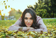 © dobok - young woman lying down on the ground in a park in autumn