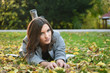 © dobok - young woman lying down on the ground in a park in autumn