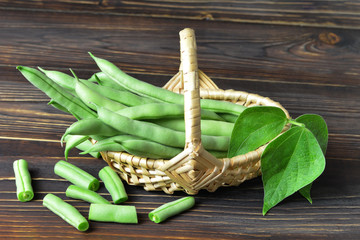 Wall Mural - Green beans in woven basket on wooden background