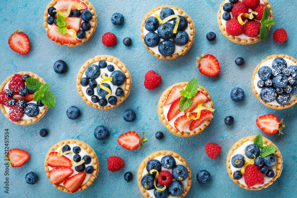 Colorful berry tartlets or cake for kitchen pattern. Pastry dessert from above. - obrazy, fototapety, plakaty 