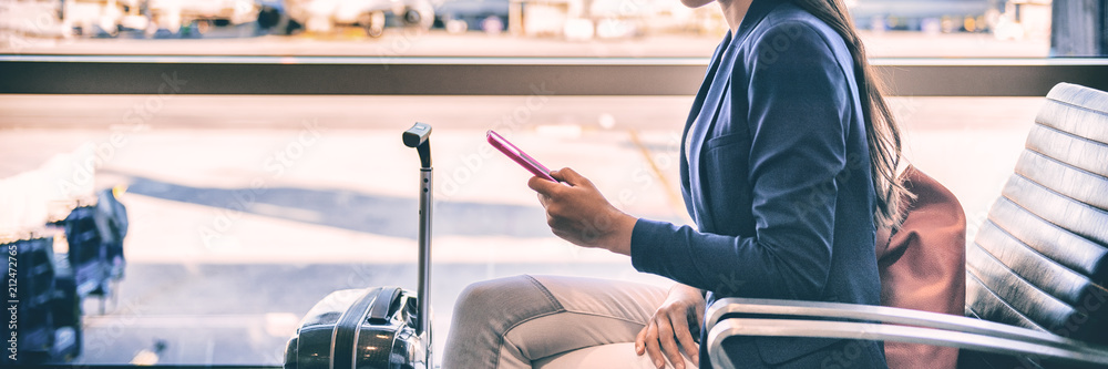 Plane passenger woman waiting for flight departure texting sms message on mobile phone at lounge airport. Businesspeople travel lifestyle panoramic banner. - obrazy, fototapety, plakaty 
