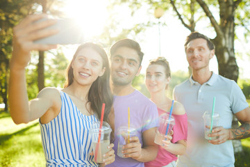 Wall Mural - Row of four happy teens posing for selfie during outdoor relax on summer day