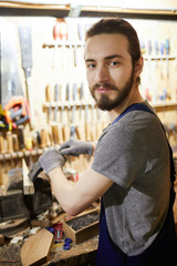 Wall Mural - Young bearded master looking at camera during work by mechanic processing machine