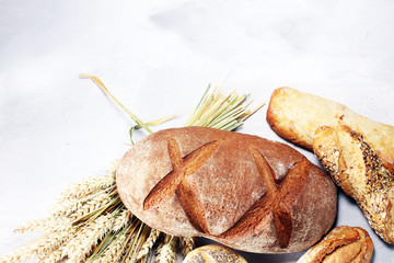 Different kinds of bread and bread rolls on board from above. Kitchen or bakery