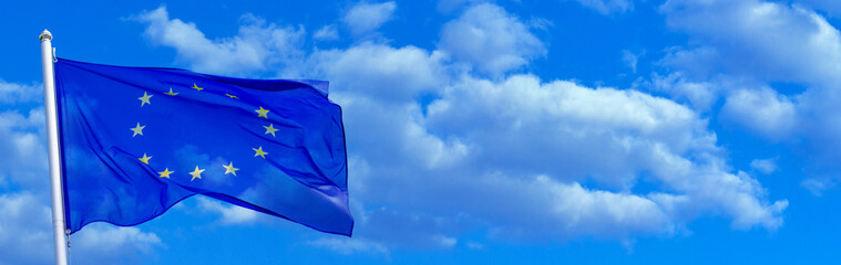 Wall Mural - Flag of the European Union waving in the wind on flagpole against the sky with clouds on sunny day, banner, close-up