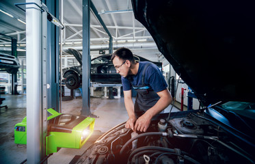 Wall Mural - Worker checks and adjusts the headlights of a car's lighting system