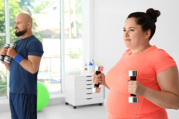 Sticker - Overweight man and woman doing exercise with dumbbells in gym