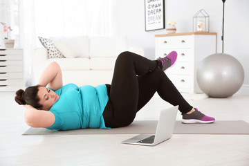 Sticker - Overweight woman doing exercise while watching tutorial on laptop at home